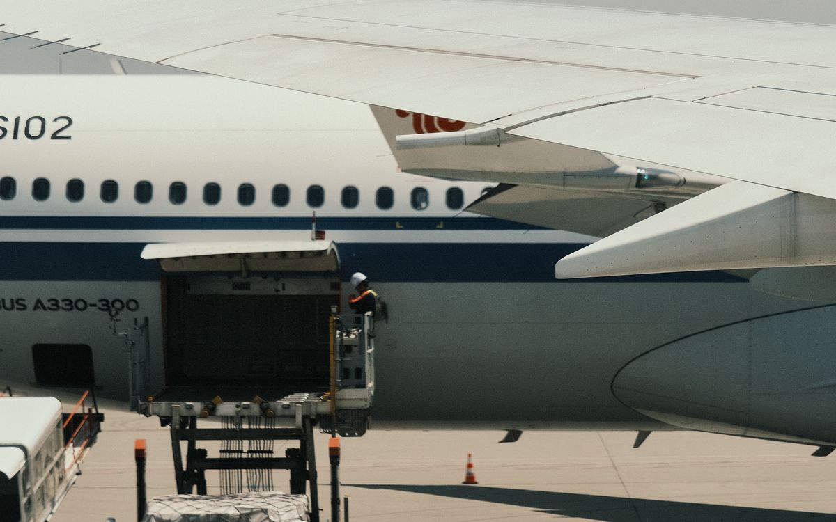 Cargador de plataforma ubicado en la puerta de carga abierta de un Airbus A330 en la rampa
